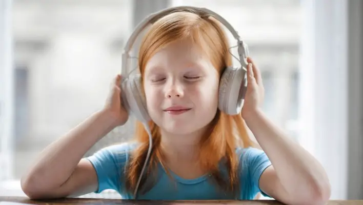 Cute little girl listening music on headphones